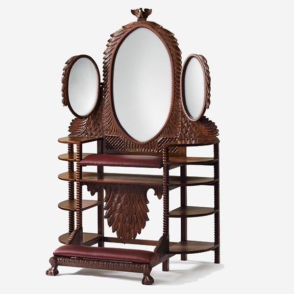 Wooden furniture vanity, with three oval mirrors, shelving, and a padded kneeling bench.