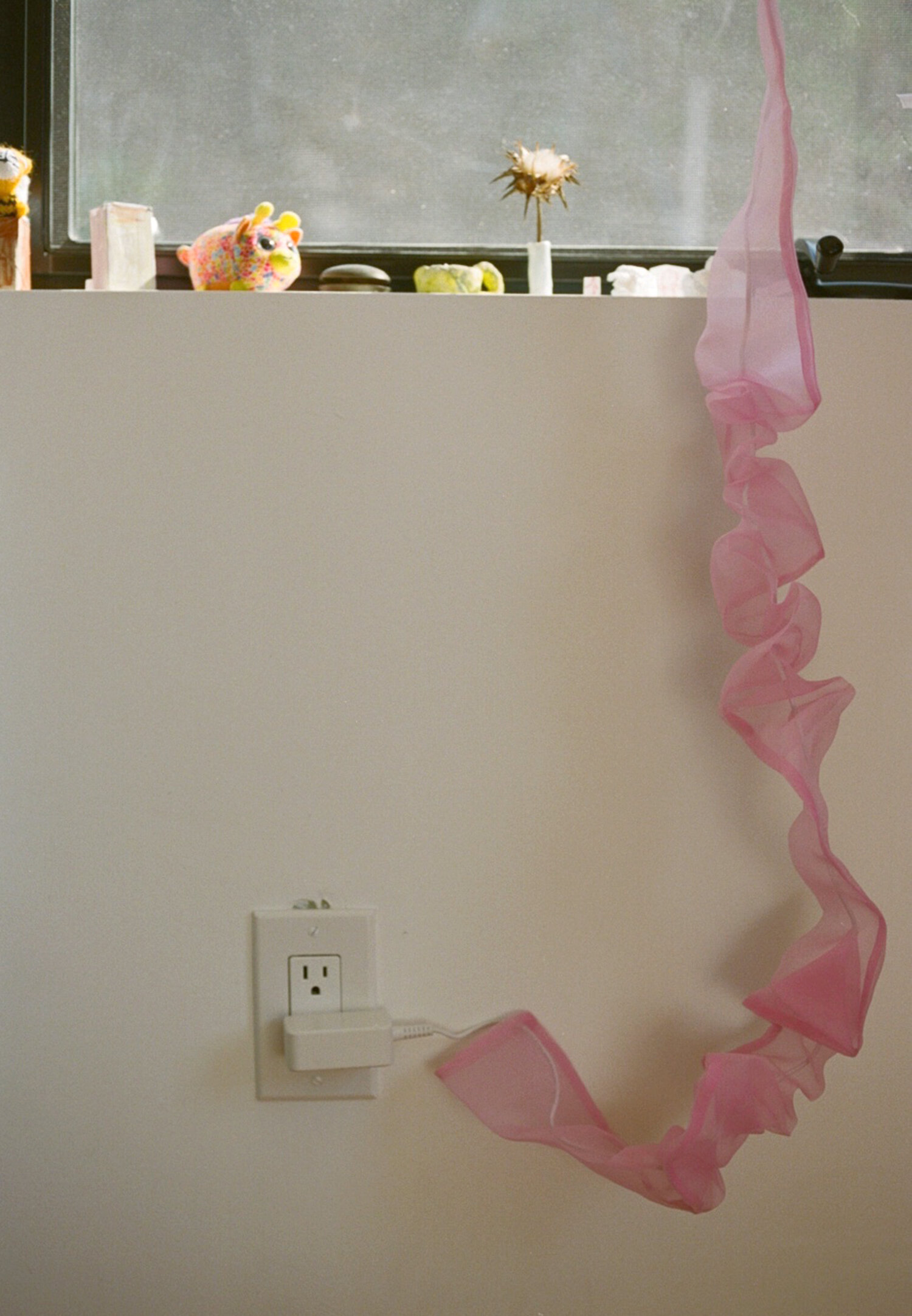 An electrical cord wrapped in a pink organza cord cover
