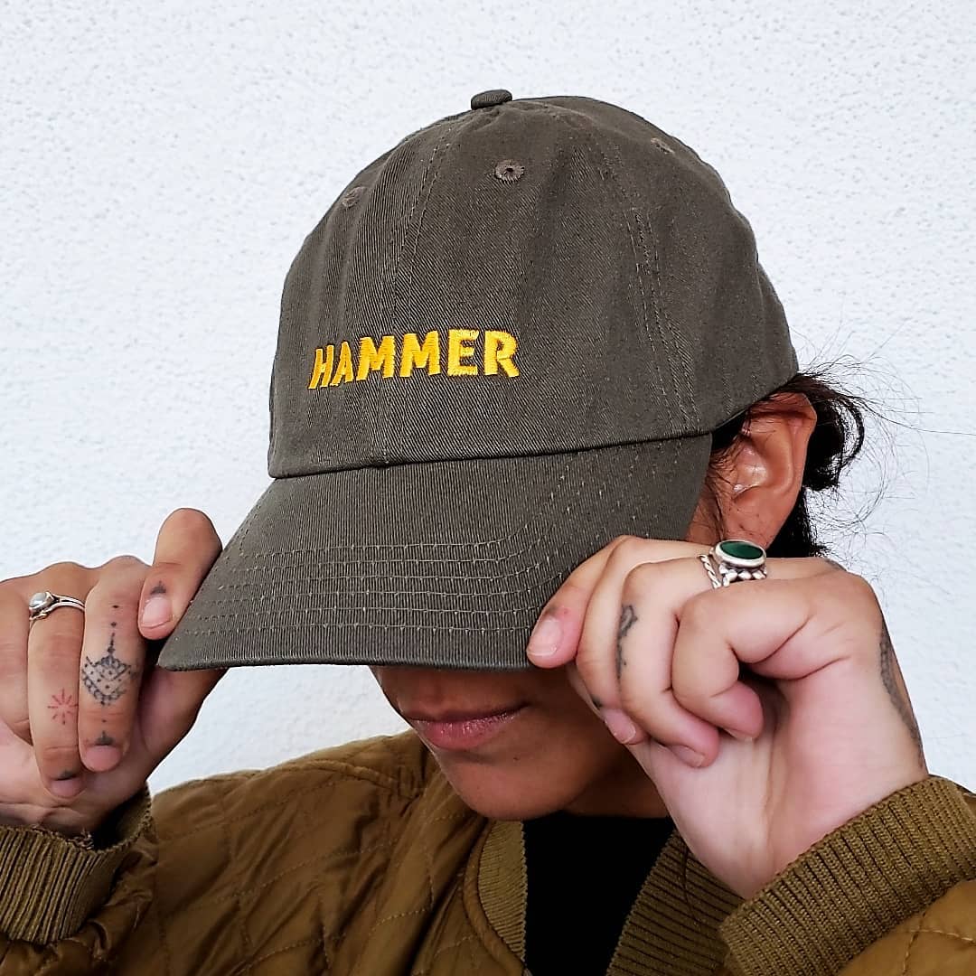 A woman wearing a tan hat that says HAMMER on it in yellow letters