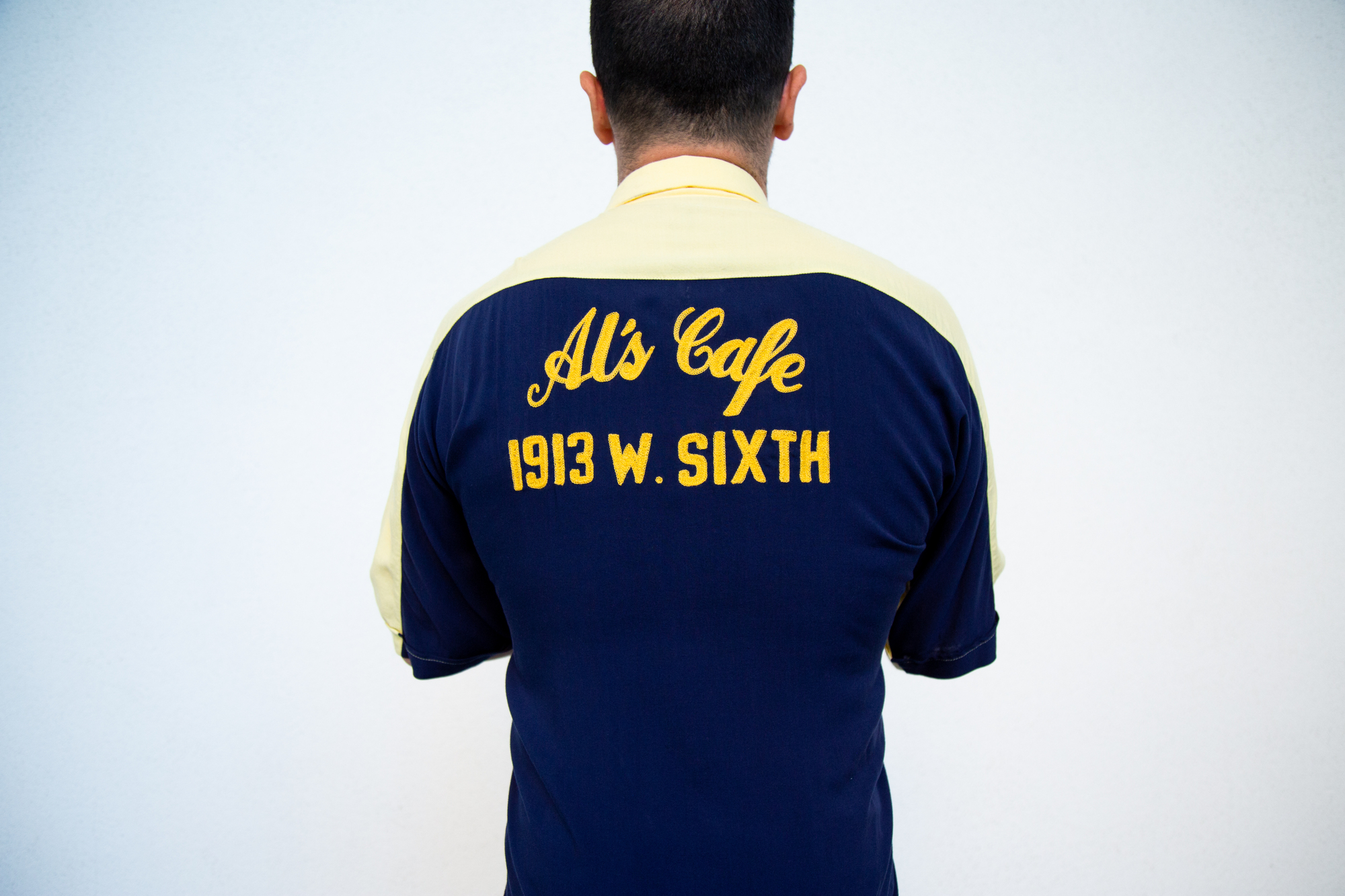 A blue shirt, seen from the back, embroidered with "Al's Cafe"