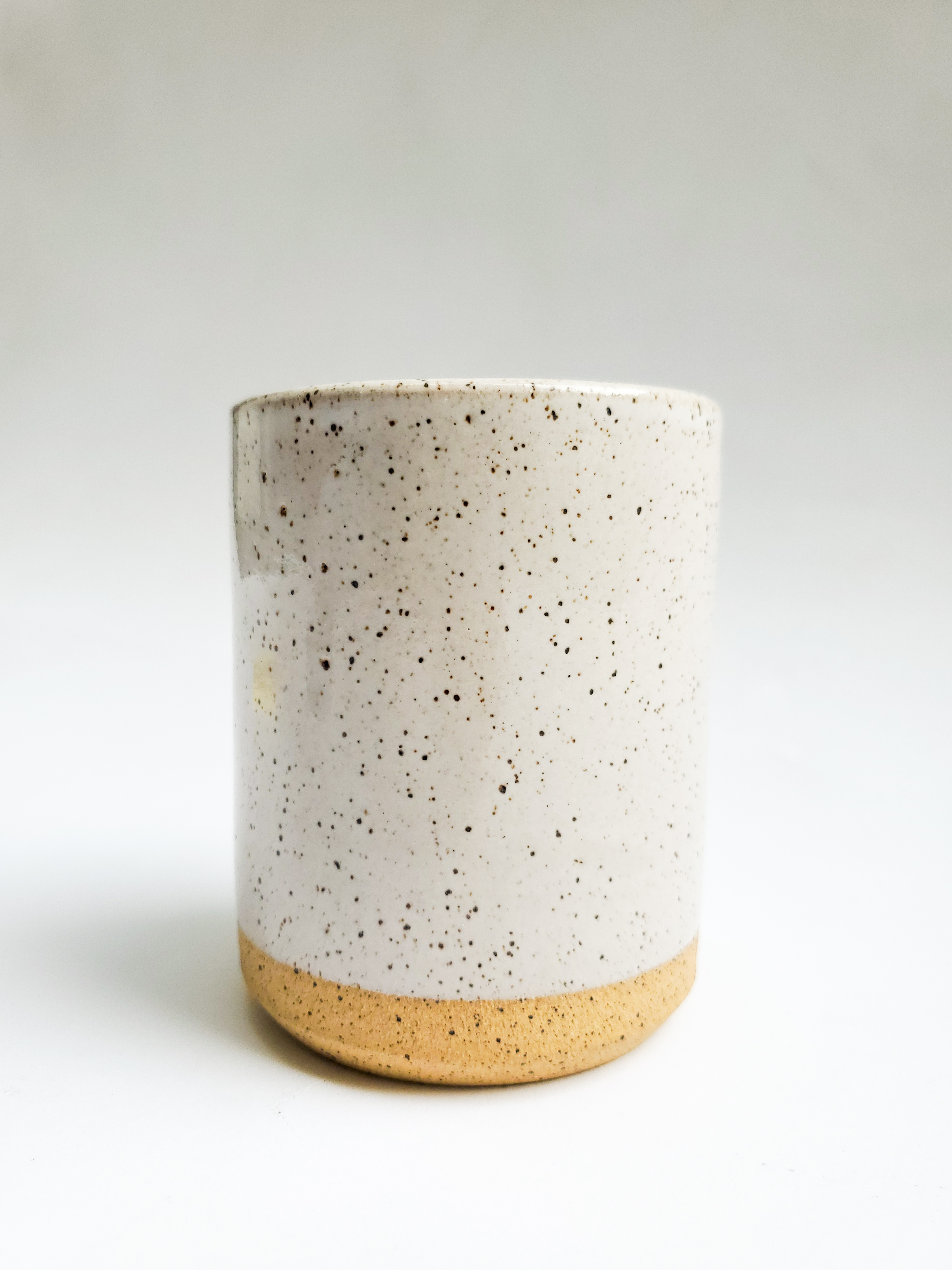 Glazed, grey, ceramic cup with black speckles. 