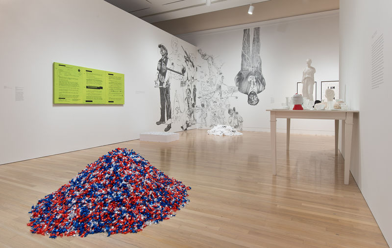 Foreground: Felix Gonzalez-Torres, "'Untitled' (USA Today)," 1990; left wall, from left to right: Jenny Holzer, "MEMORANDUM FOR CONDOLEEZZA RICE GREEN," 2006, and Felix Gonzalez-Torres, "'Untitled' (Death by Gun)," 1990, on floor; corner: Rirkrit Tiravanija, "untitled 2014 (up against the wall motherfucker)," 2014; right wall: Fred Wilson, "Love and Loss in the Milky Way," 2005. Installation view at the Hammer Museum, Los Angeles