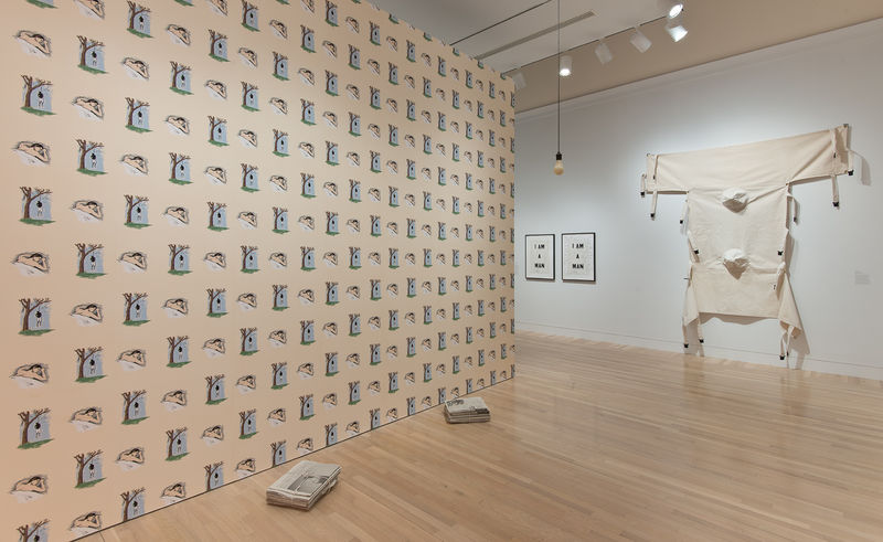 Left wall: Robert Gober, "Hanging Man/Sleeping Man," 1989; right wall, from left to right: Glenn Ligon, "Condition Report," 2000, and Nayland Blake, "Dual Restraint," 1990; from ceiling, Robert Gober and Sherrie Levine, "Untitled," 1990; on floor: two works from Robert Gober's Newspaper series, 1992. Installation view at the Hammer Museum, Los Angeles