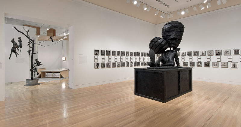 On floor: Paul McCarthy, "Michael Jackson Fucked Up Big Head Big Foot (MJFUBH)," 2010. On wall: Glenn Ligon, "Notes on the Margin of the 'Black Book,'" 1991–93. In next gallery: works by Mark Dion and Stephen Prina. Installation view at the Hammer Museum, Los Angeles