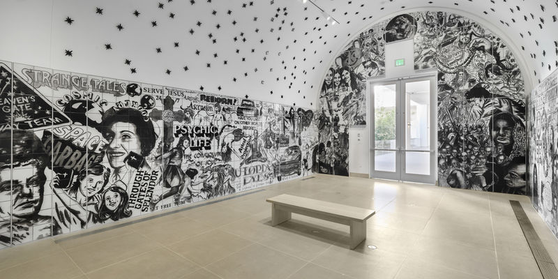 Vault installation featuring a floor-to-ceiling ceramic mural with black-and-white graphics, text, and images of people