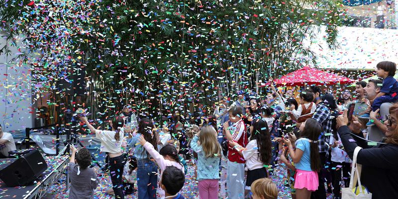 kids standing in a museum courtyard, watching confetti fall around them