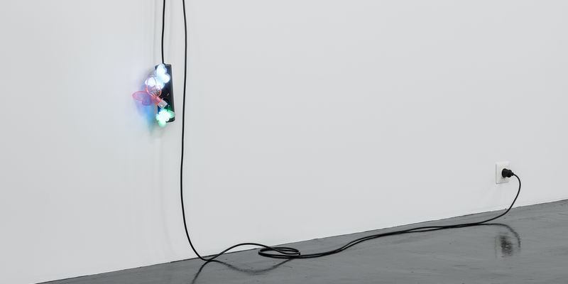 A black extension cord hangs from a wall, with three butterfly nightlights plugged into it