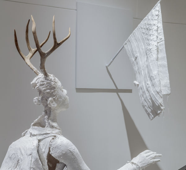 Life-sized plaster figure of a girl with deer antlers, climbing the stairs 