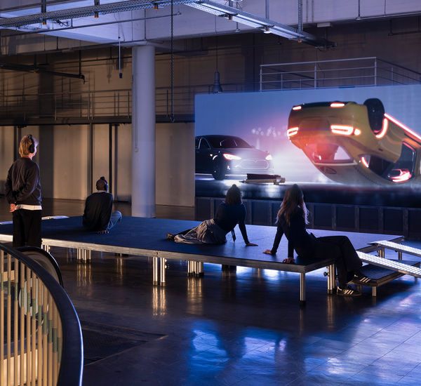 Gallery view of visitors watching a video with an overturned car