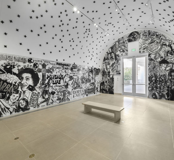 Vault installation featuring a floor-to-ceiling ceramic mural with black-and-white graphics, text, and images of people