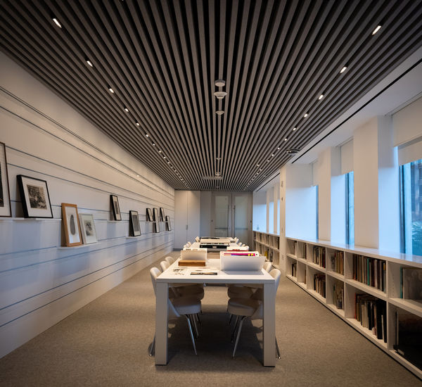 Empty room with tables and walls covered in works on paper