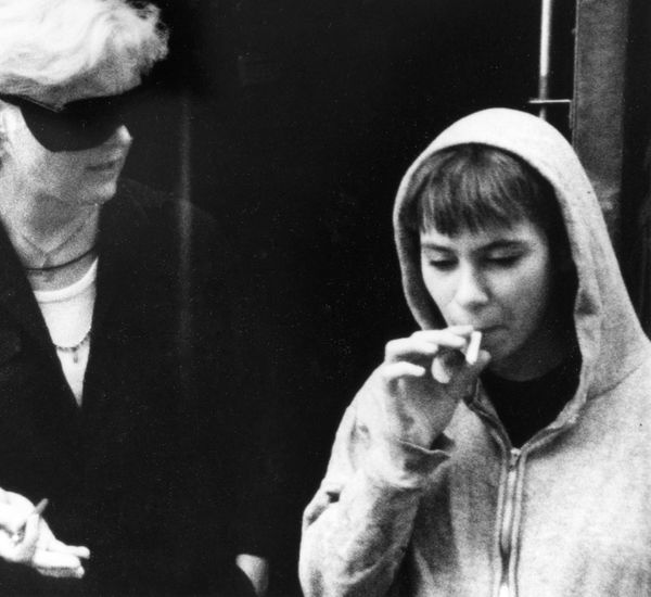 Three people smoke cigarettes and talk