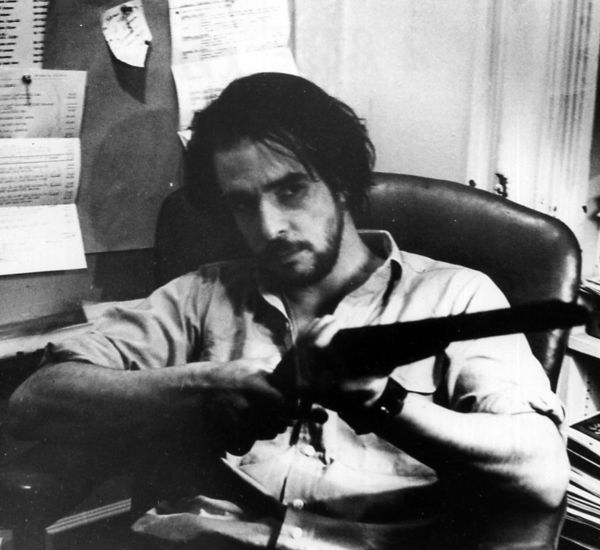 still from ice of a man sitting pointing a shotgun