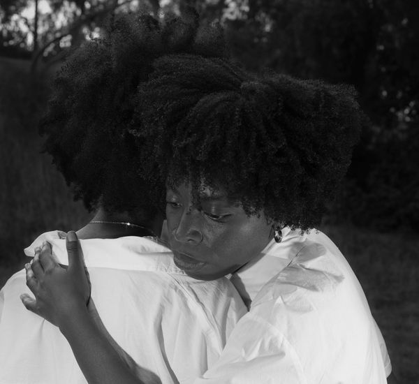 Two Black woman embrace each other