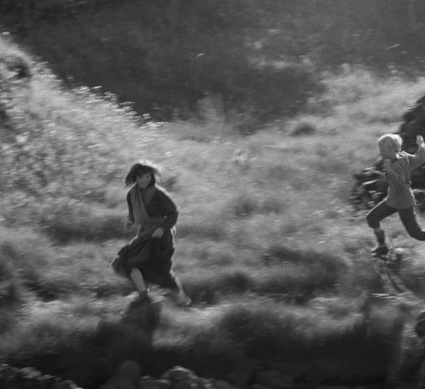 girl and boy running through field, b&w