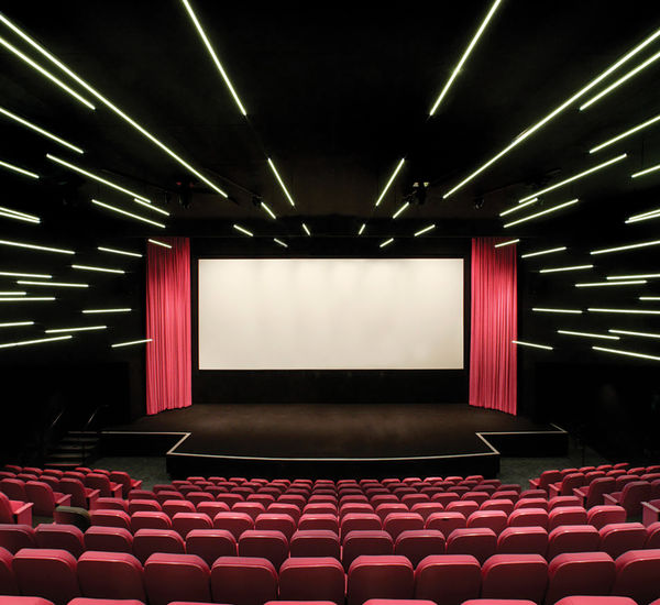 An empty movie theater with pink curtains and seats