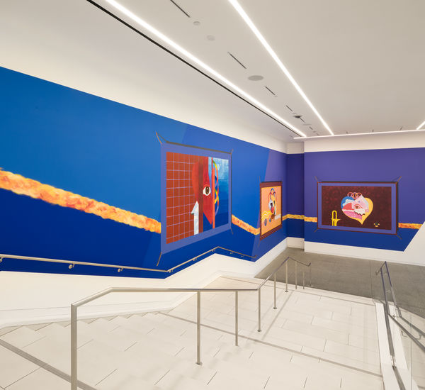 Mural on a bright blue background, installed along a large museum stairway