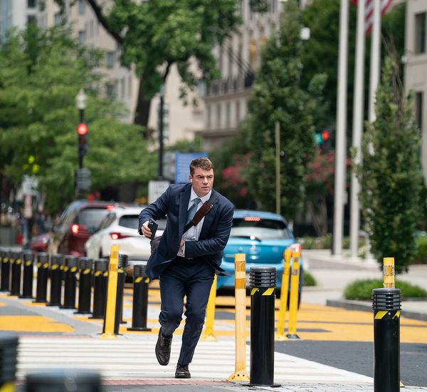 A man in a blue suit runs down a city street