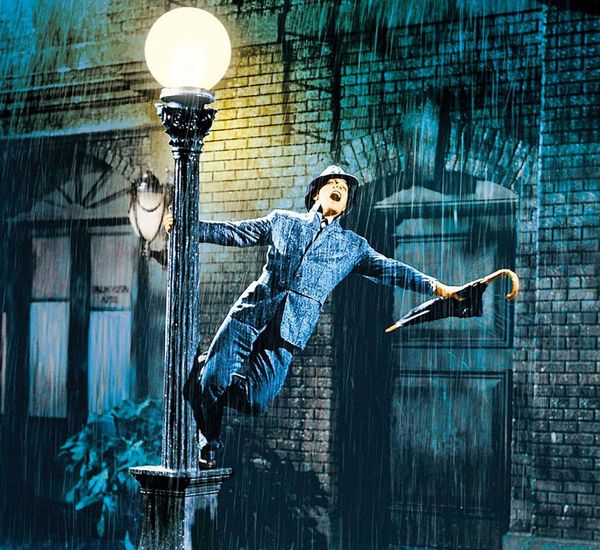 Gene Kelly spins around a lamppost in the rain