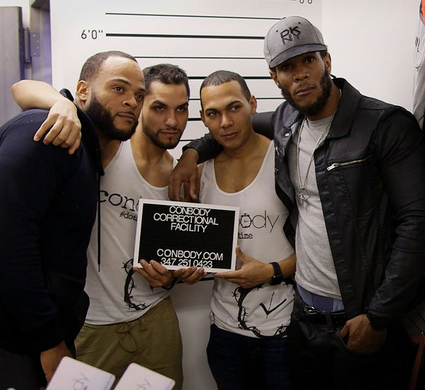 Four men pose with a sign reading "Conbody Correctional Facility"