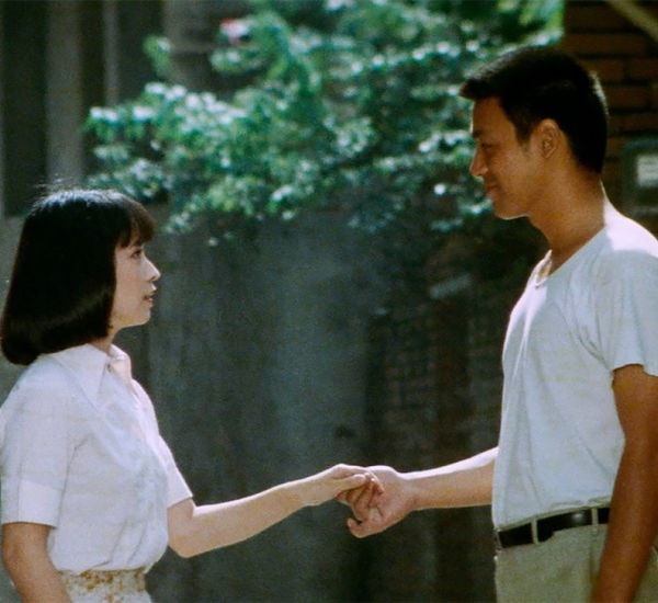 A man and woman hold hands and look into each other's eyes