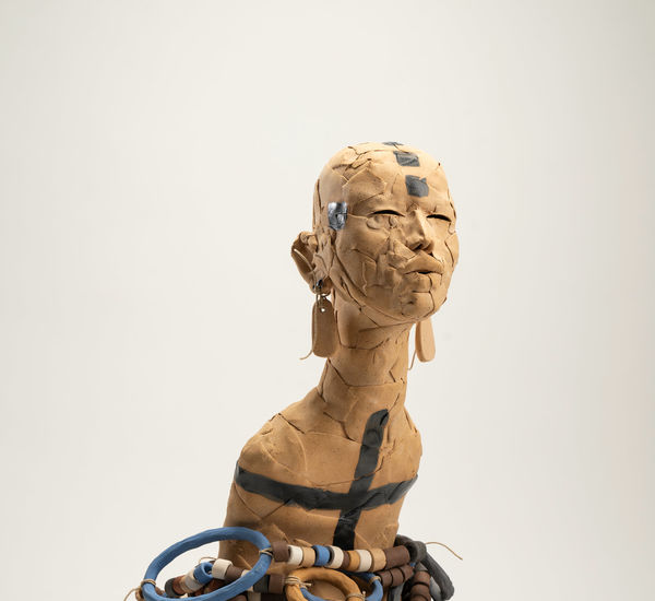 Ceramic figure with long earrings, body enveloped in beaded necklaces