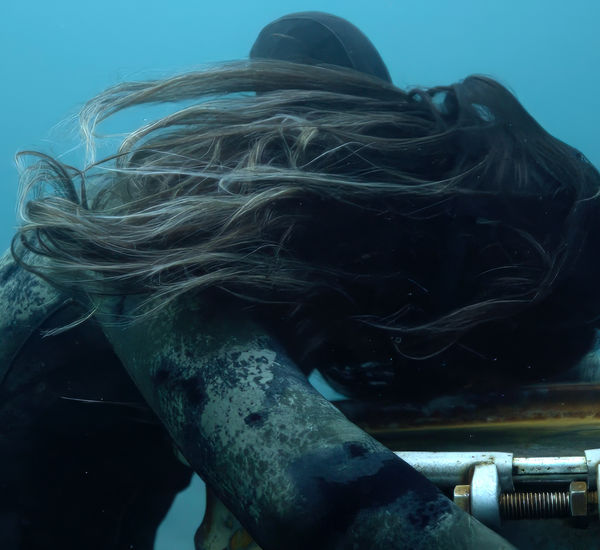 Underwater scene of a diver holding onto a sunken barrel