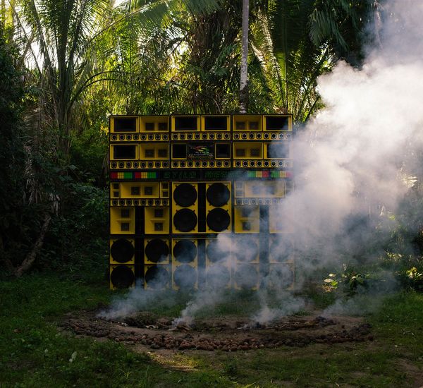 A wall of yellow speakers, surrounded by smoke