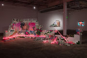 Installation featuring a crumbling wall of cinderblocks with handpainted images and pink neon lights