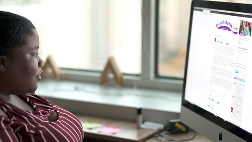 A woman in profile looks at a computer screen