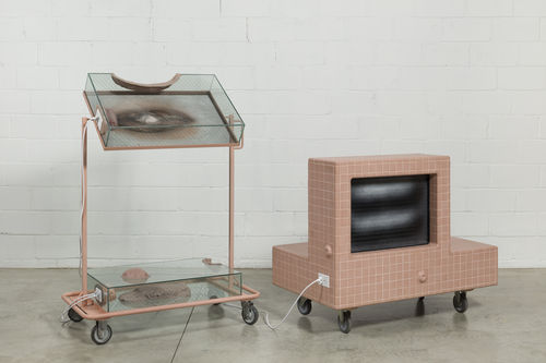A pink TV monitor hooked up to a rolling stand