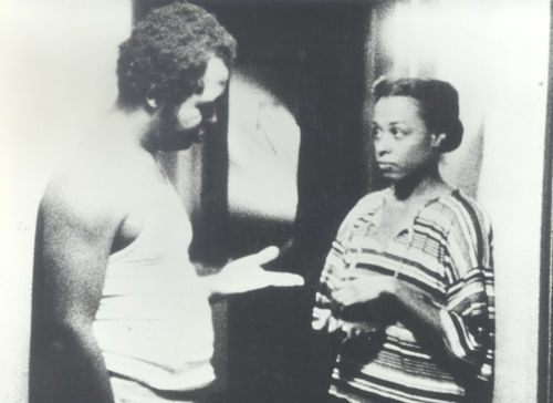 Still from the film Bless Their Little Hearts (1984) showing a man and a women speaking in a hallway