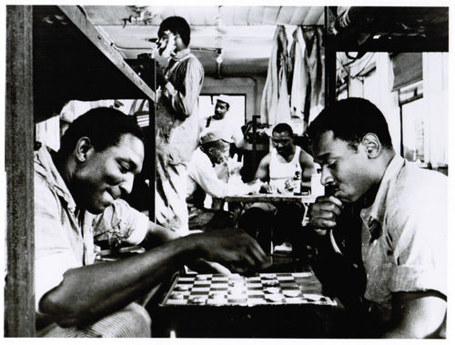 Still from the film Nothing But a Man (1964) showing men playing checkers in a crowded room in a 
