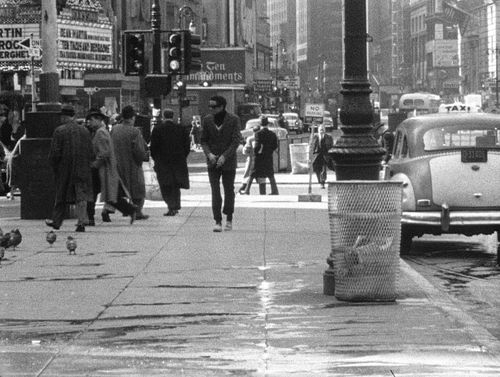 Still from the film Shadows (1961) showing a man walking down a busy city sidewalk