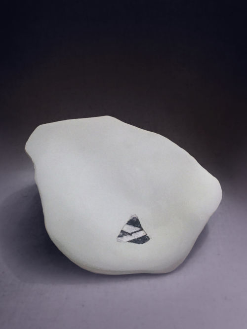 A white stone with a small black-and-white cutout on a grey background