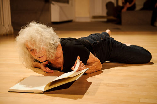 A woman lies on the ground, looking into an open book