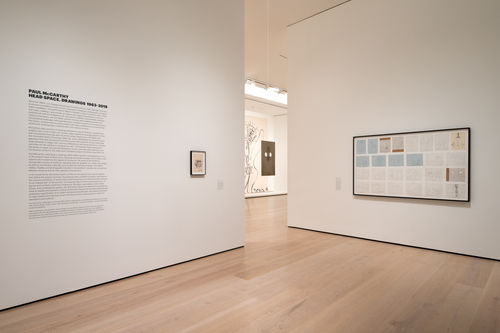 A view of perpendicular gallery walls, with a space between looking into the next room