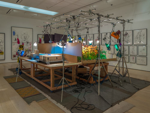 A plywood table with a maquette of a set with colorful stage lamps hanging above