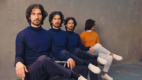 Four men sit in a line, the last man looking away