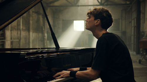 A young man sits at a piano