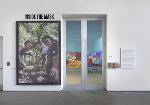 A large photograph of three men in a mask next to a set of double glass doors