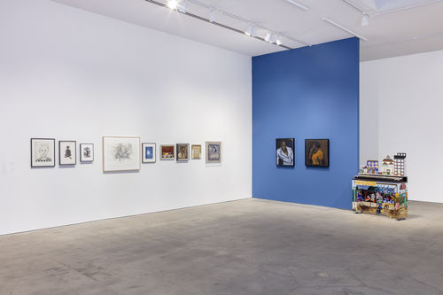 A gallery with a white and a blue wall with several artworks hanging