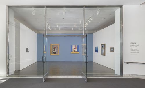 A view of the gallery from outside, shown through windows and glass doors