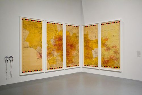 A gallery wall where five yellow map panels hang