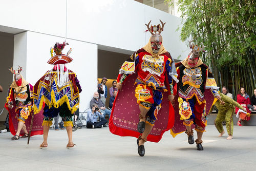 Dancers in deer masks move around a courtyard