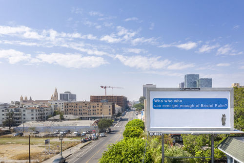 View of a city with blue sky and a billboard in the foreground. Against a white background, a message is typed as if a text message: "Who Who Who Can ever get enough of Bristol Palin?" An owl figure is depicted on lower right pf the billboard. 