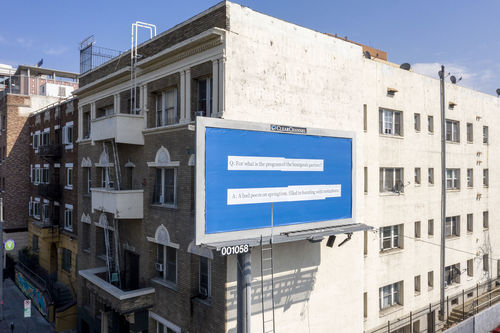 A billboard against the side of a four-story building reads "Q: For what is the program of the bourgeois parties:? A: A bad poem on springtime, filled to bursting with metaphors."
