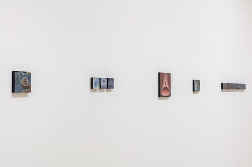 Small paintings hang on a white wall