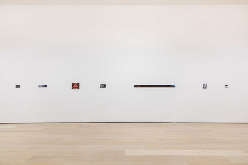 Small paintings hang on a white wall