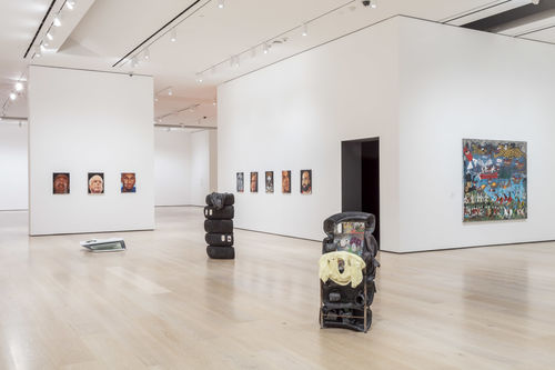 Three sculptures made of mixed objects are displayed prominently in a gallery
